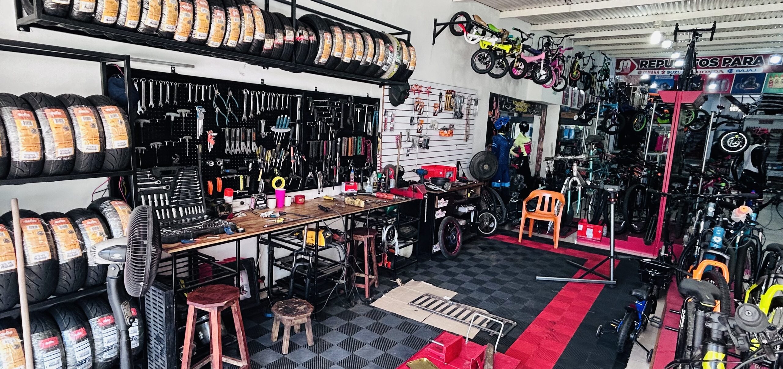 Taller de bicicletas de JM Repuestos con herramientas, llantas y bicicletas en exhibición